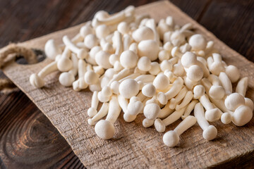 Fresh white beech mushrooms elegantly arranged on a rustic cutting board