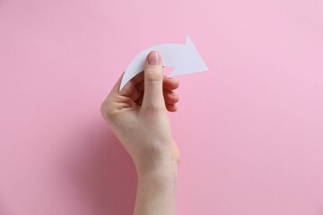 Woman with paper arrow on pink background, top view