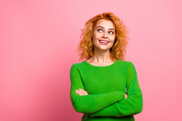 Smiling young woman in green sweater posing against a pink background, expressing happiness and positive feelings