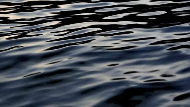 Calm dark water surface with gentle ripples, abstract nature background. Tranquility and reflection concept