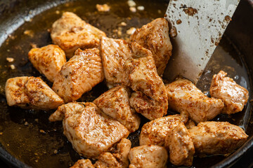Chicken fillet pieces are fried in a frying pan in spices and turned over