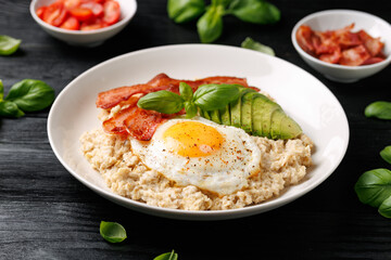 Savory Oatmeal breakfast with sunny side up fried egg, bacon and avocado. Healthy food