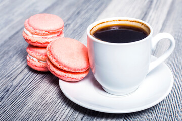 Cup of coffee and french macaron on an wooden table.