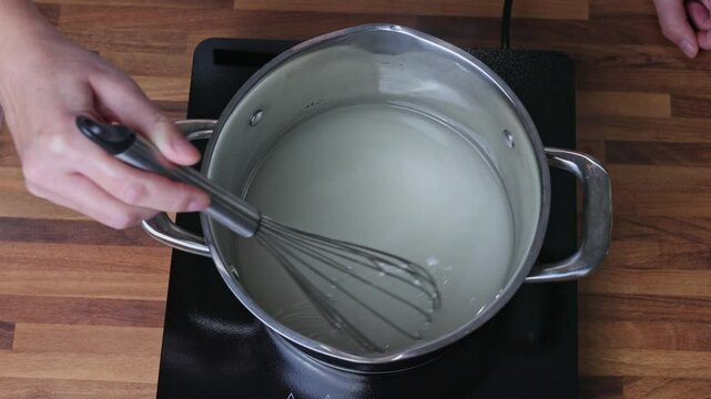 Preparing sugar syrup for cooking tangerine jam in a saucepan on the stove in a home kitchen