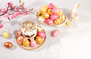 Abstract Easter composition with traditional Russian kulich with meringue and decorated painted eggs on elegant table with spring sakura flowers. Happy Easter concept. Banner for screen