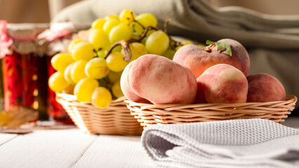 Fruit of peaches and grapes in bowls on white wooden table with cozy indoor background.