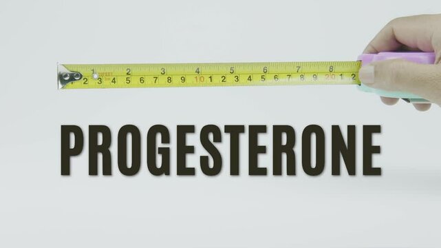 "Progesterone" text with a yellow tape measure on a white background, symbolizing precision, accuracy, and the measurement of hormone levels and reproductive health in a clean, minimal video