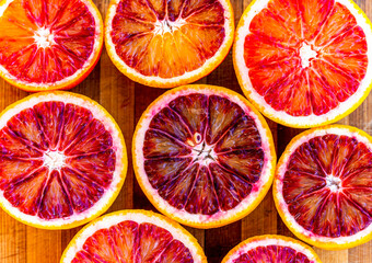 Red blood halved oranges close up on a wood background. Top view. Flat lay of fresh orange citrus...