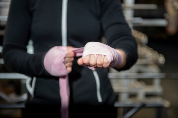 Boxer wrapping hands with pink bandages in gym