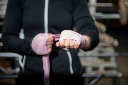 Boxer wrapping hands with pink bandages in gym - Powered by Adobe