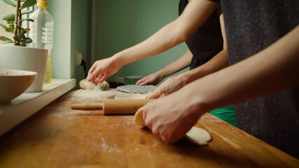Hands preparing dough on wooden surface while holding dumpling mold. Flattening dough for shaping into dumplings. Positioning dough and tools carefully for precise preparation process