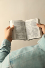 Man reading Holy Bible in English language on light background, closeup