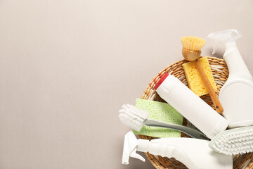 Bottles of different cleaning products and tools on beige background, top view. Space for text
