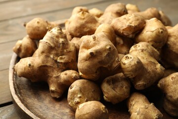Raw Jerusalem artichokes on wooden table, closeup