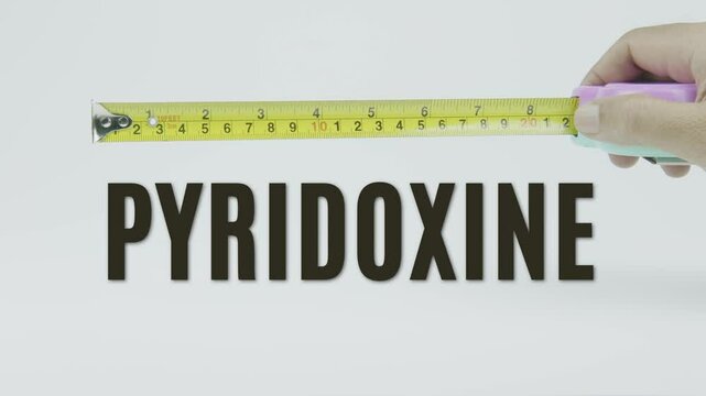 "Pyridoxine" text with a yellow tape measure on a white background, symbolizing precision, accuracy, and the measurement of vitamin B6 levels and nutritional balance in a clean, minimal video