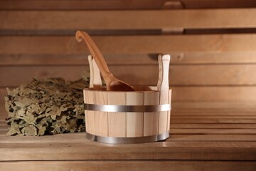 Bucket, ladle and whisk on wooden bench in sauna
