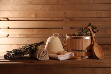 Bucket, whisks, massaging brushes and other equipment on wooden bench in sauna