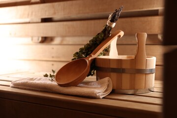 Ladle, towel, bucket and whisk on wooden bench in sauna