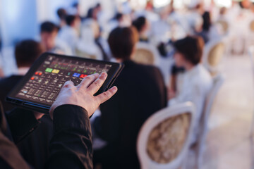 View of lighting technician with tablet, operator controlling sound and light during live event...