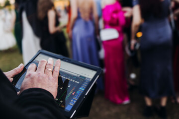 View of lighting technician with tablet, operator controlling sound and light during live event...