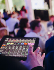 View of lighting technician with tablet, operator controlling sound and light during live event...