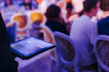 View of lighting technician with tablet, operator controlling sound and light during live event...