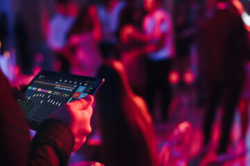 View of lighting technician with tablet, operator controlling sound and light during live event...