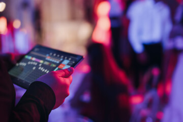 View of lighting technician with tablet, operator controlling sound and light during live event...