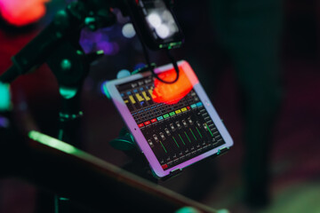 View of lighting technician with tablet, operator controlling sound and light during live event...