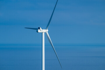 offshore wind turbine against blue ocean sky. © Trygve