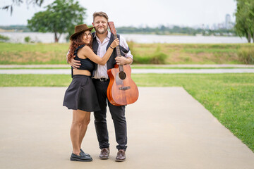 Couple of musicians pose looking at the camera in a park