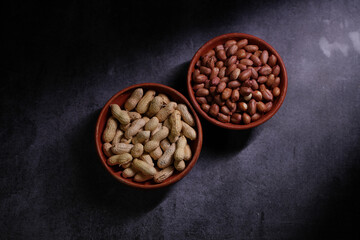 One bowl contains unshelled peanuts. Another bowl contains shelled peanuts.