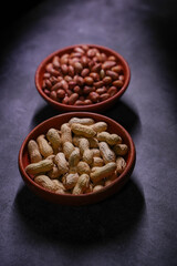 One bowl contains unshelled peanuts. Another bowl contains shelled peanuts.