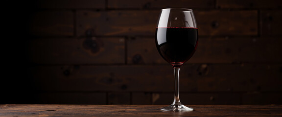 Elegant wine glass filled with rich red wine against a warm, rustic wooden background exuding sophistication and inviting indulgence