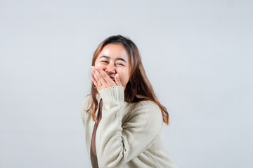 A young woman laughs heartily, covering her mouth with her hand. Her genuine expression of joy and casual style make this image perfect for lifestyle and emotion-related projects.