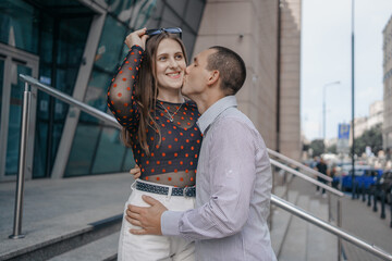 Young couple in love sitting on stairs, talking. Smiling beautiful woman and her handsome boyfriend. Couple in casual summer clothes. Happy cheerful family. Sit at stairs.