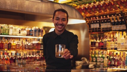 Smart Asian bartender using stirring mixed alcohol syrup into glass with ice for on the rock served mixing looking camera zoom out special refresh cocktail nightlife mixology at nightclub. Vinosity.