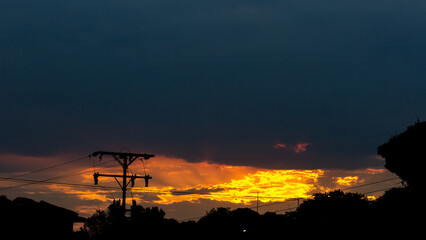 Sunset over the city with orange sky and silhouette of electric pole