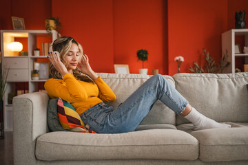 Obraz premium relax young girl enjoy on sofa and listen music on headphones