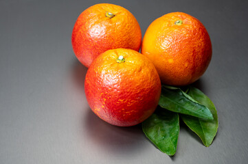 Sicilian sweet juicy yellow and red blood oranges with green leaves close-up