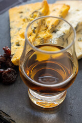 Whiskey and cheese pairing, tasting whisky glass and plate with sliced blue stilton and blue shropshire cheeses, Great Britain food and drink