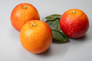Sicilian sweet juicy yellow and red blood oranges with green leaves close-up
