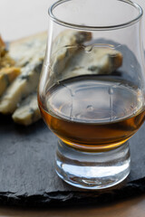 Whiskey and cheese pairing, tasting whisky glass and plate with sliced blue stilton and blue shropshire cheeses, Great Britain food and drink