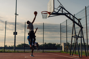 Two basketball players trying alley oop on outdoor court