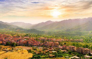 Obraz premium scenic panorama of italian town during sunset with amazing view from above to nice city with picturesque mountain valley landscape and cloudy sky on backdrop