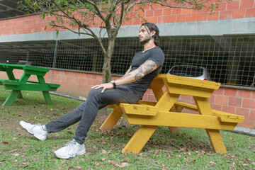 Young man sitting on a bench in a park outdoors