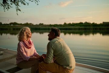 Romantic senior couple holding hands and enjoying a peaceful sunset boat ride on the lake