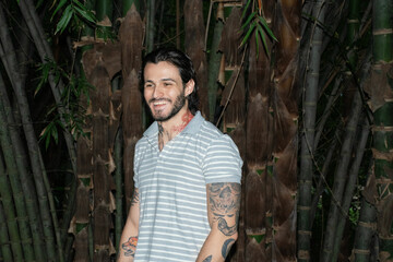 Young tattooed man portrait surrounded by nature outdoors.