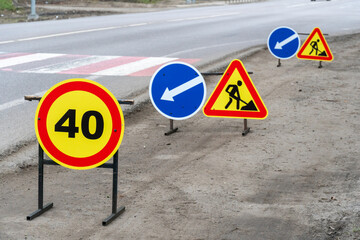 Road signs alerting drivers of a 40 km/h speed limit, direction of travel, and ongoing construction near a crosswalk area