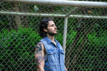 Young tattooed man standing next to a soccer goal in a park surrounded by nature